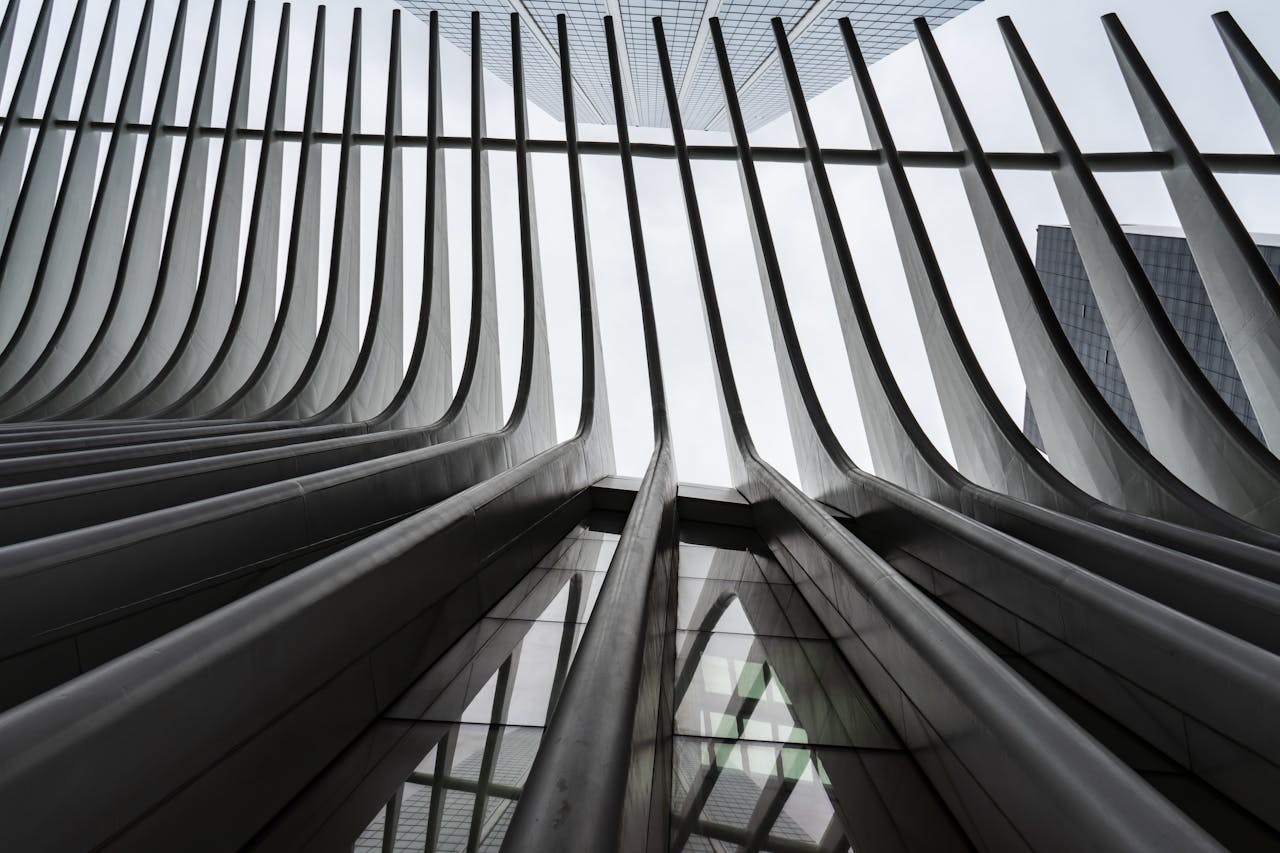 Upward view of modern architectural structure with curved steel beams and glass panels.