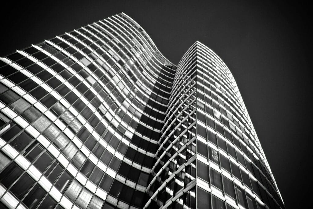 Black and white view of a modern skyscraper with a curved facade and grid-like window patterns.