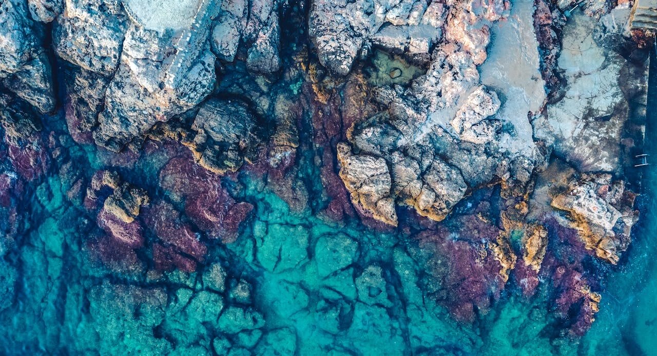 Aerial Photography of Rocks Beside Body of Water