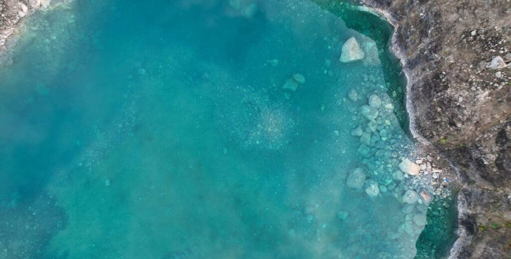 Aerial view of a turquoise water pool in a stone quarry.